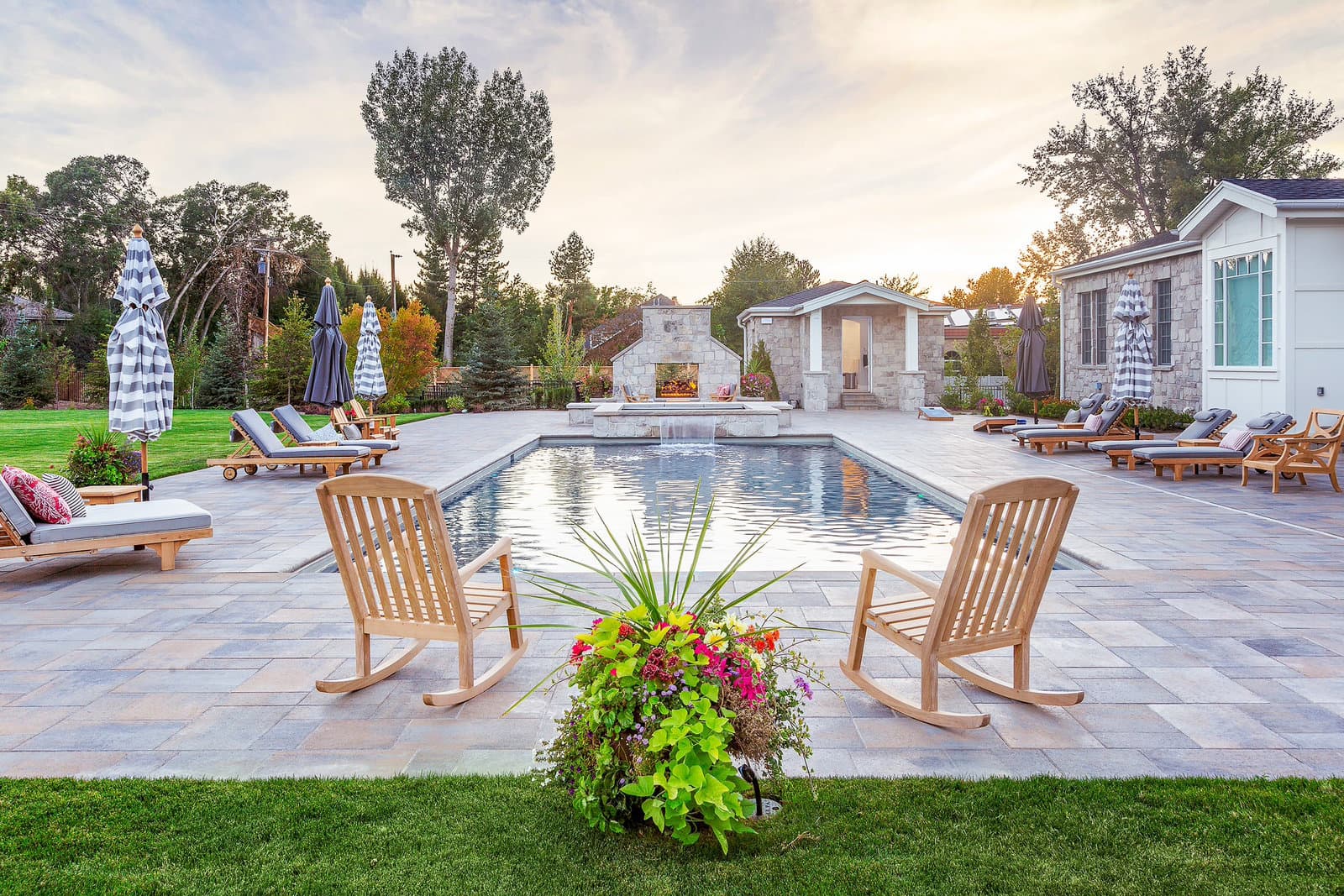 Mature, professionally maintained Big Rock classic landscape with pool, manicured plantings, and Adirondack lounge chairs in Cottonwood Heights, Utah
