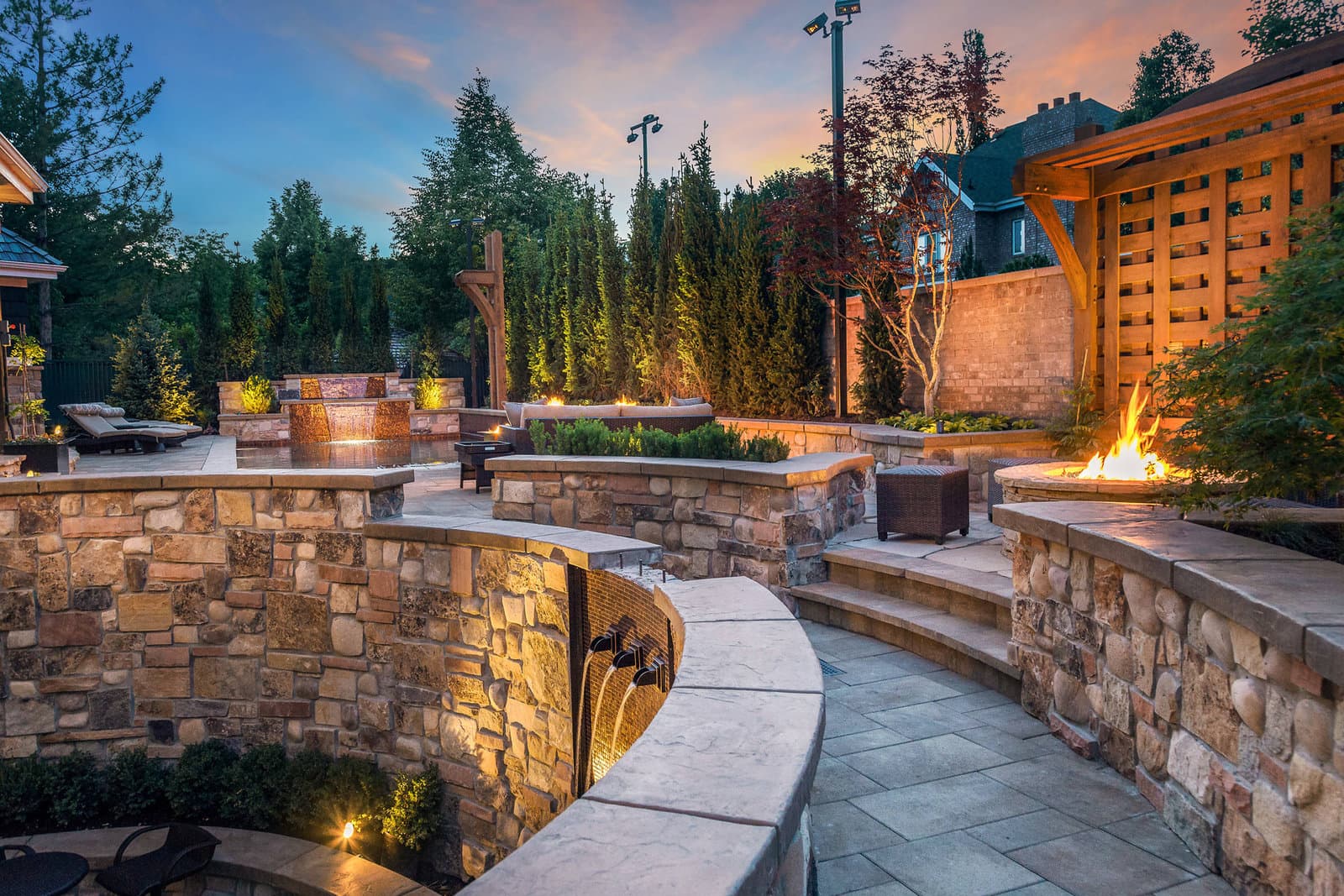 Big Rock custom waterfall cascading down hand-set stone walls beside a fire feature and pergola at a Provo Vintage Estates residence