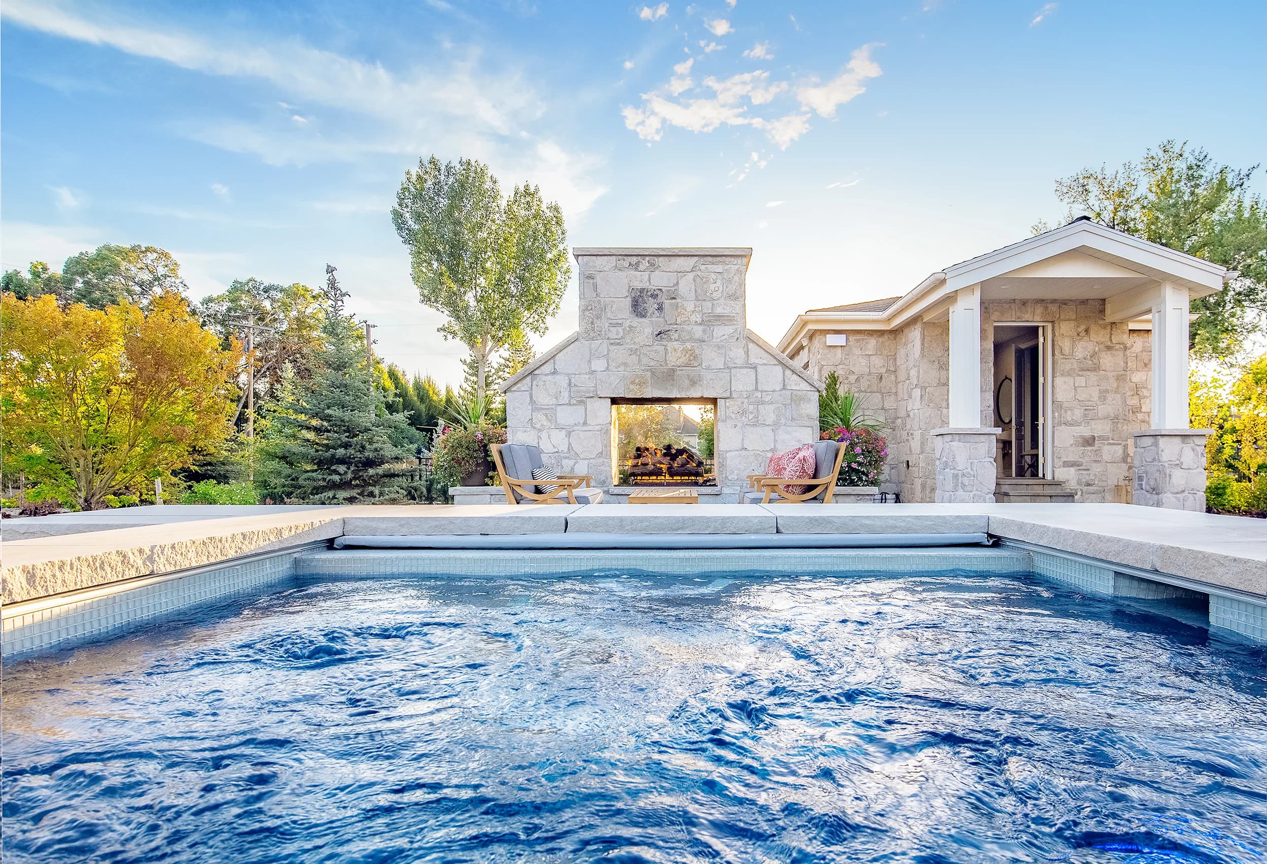Big Rock pool with stone fireplace pavilion centered between mature plantings on a Wasatch Front estate