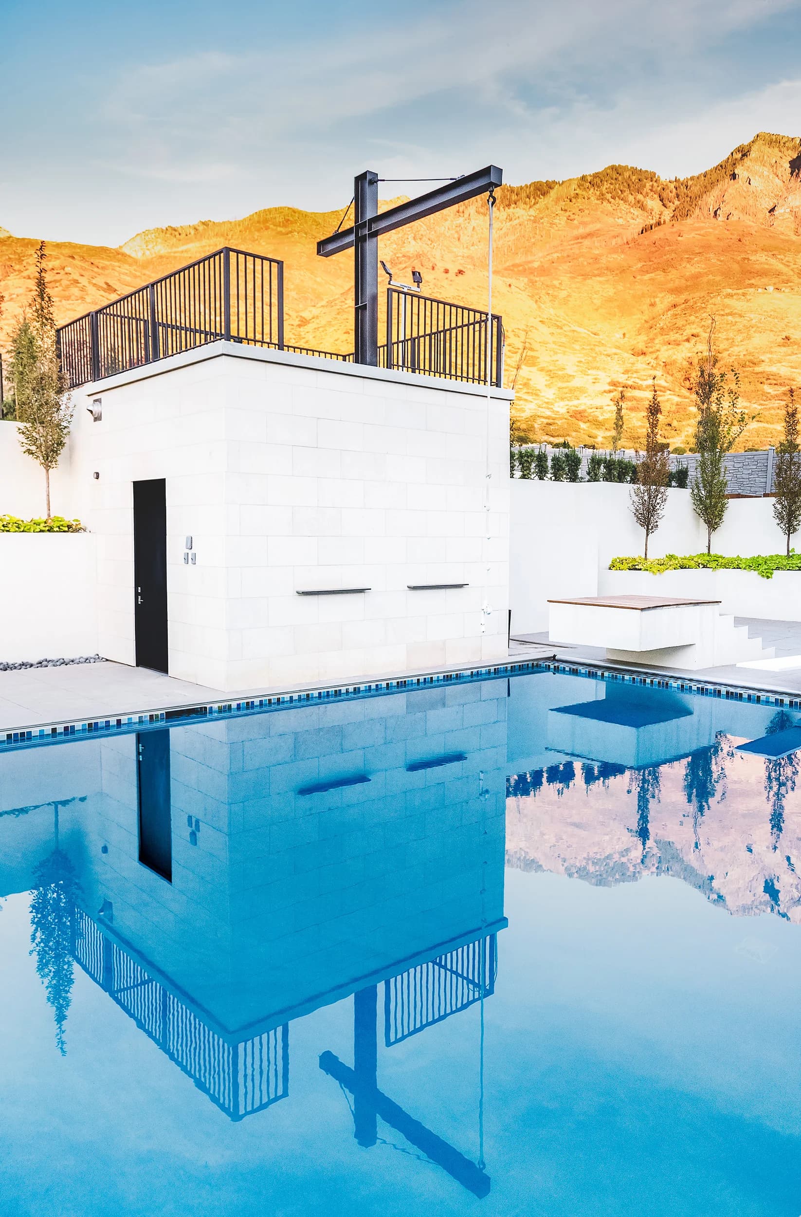 Bright daylight Big Rock pool deck with crisp white poolhouse and Wasatch Front mountains beyond