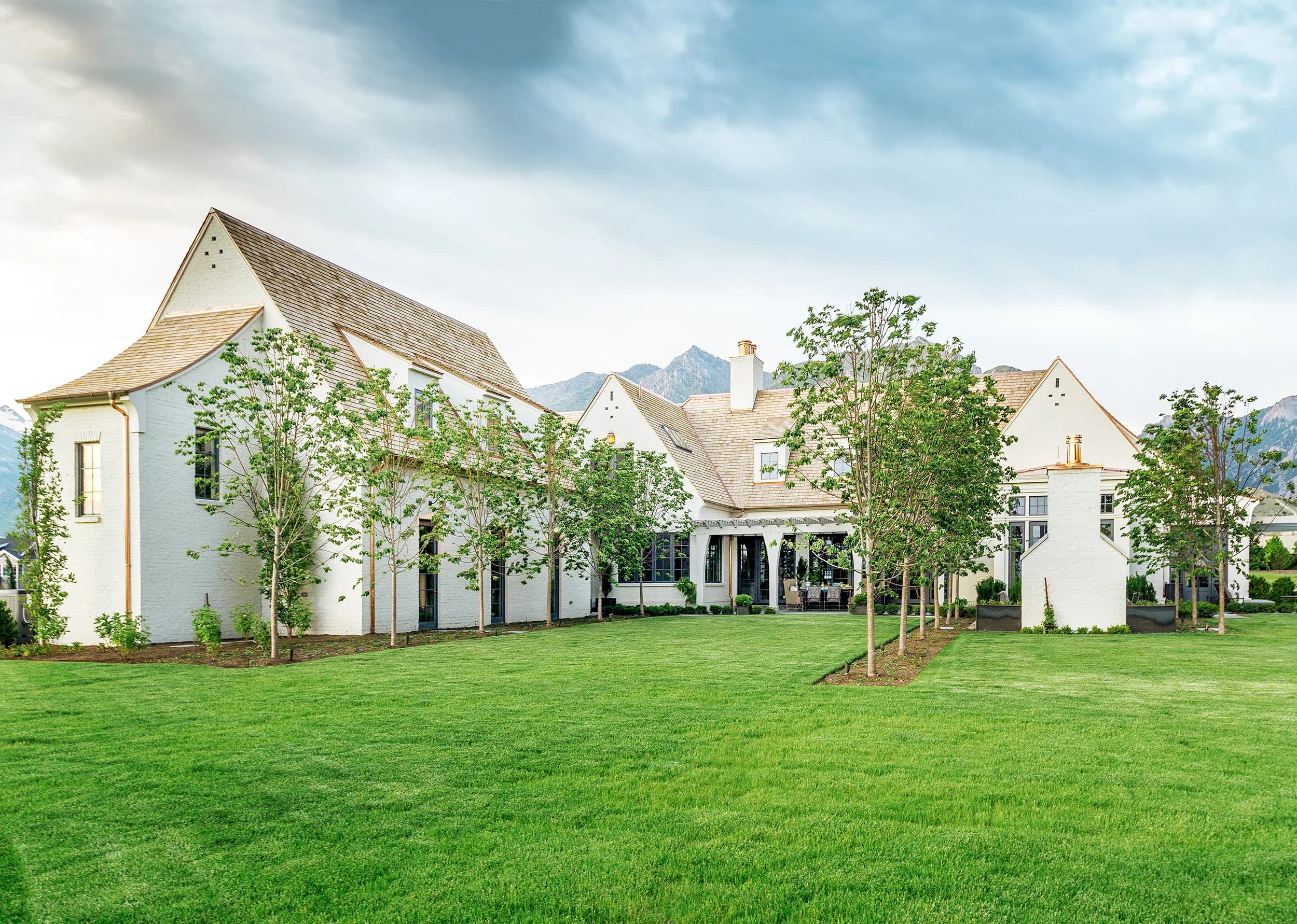 Sweeping lawn fronting a white Big Rock estate with the Wasatch peaks rising in the distance